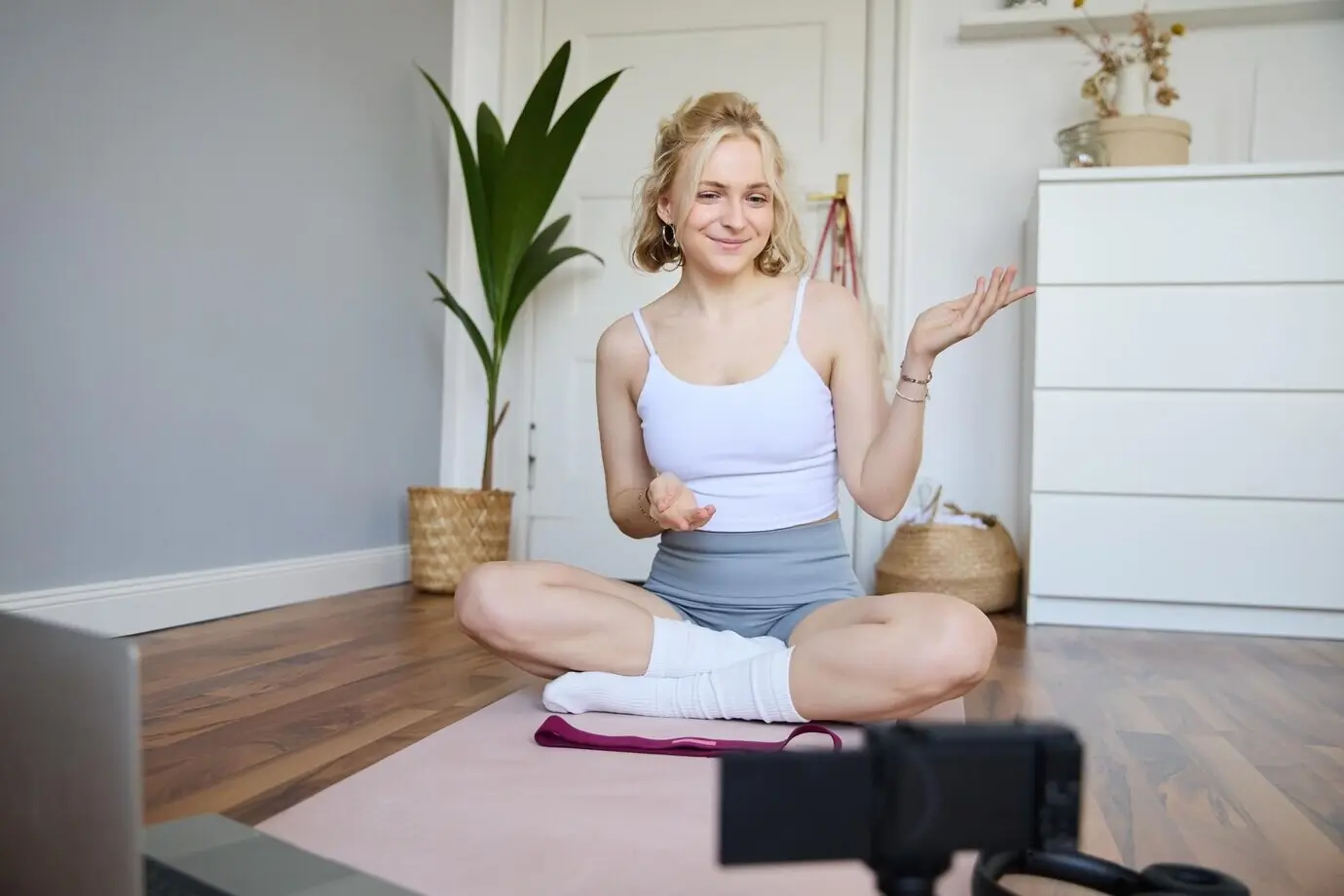 Porträt eines schönen Fitness-Bloggers, der mit einer Digitalkamera ein Video aufnimmt und Workout-Übungen zeigt.
